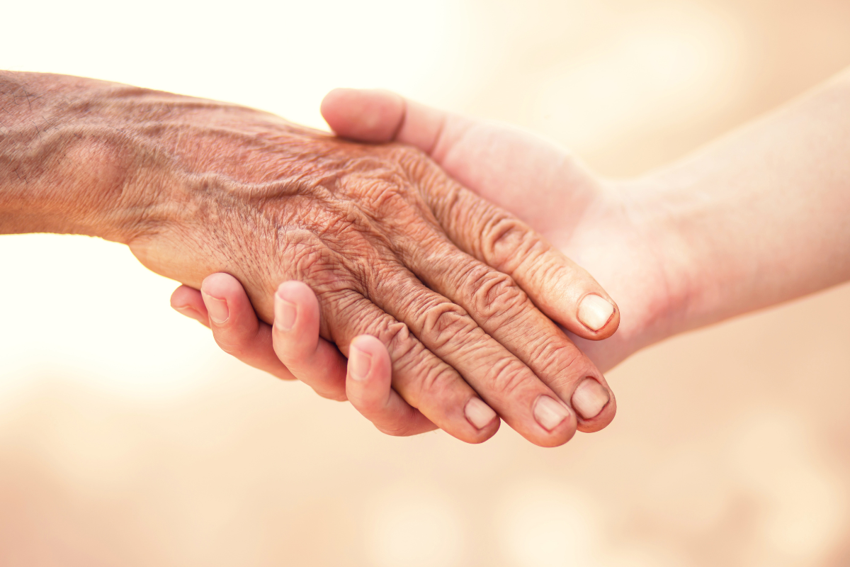a mão de um médico da área da psiquiatria geriátrica segurando a mão de um paciente idoso